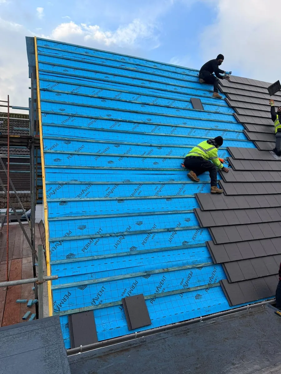 Roofer laying grey tiles over blue membrane