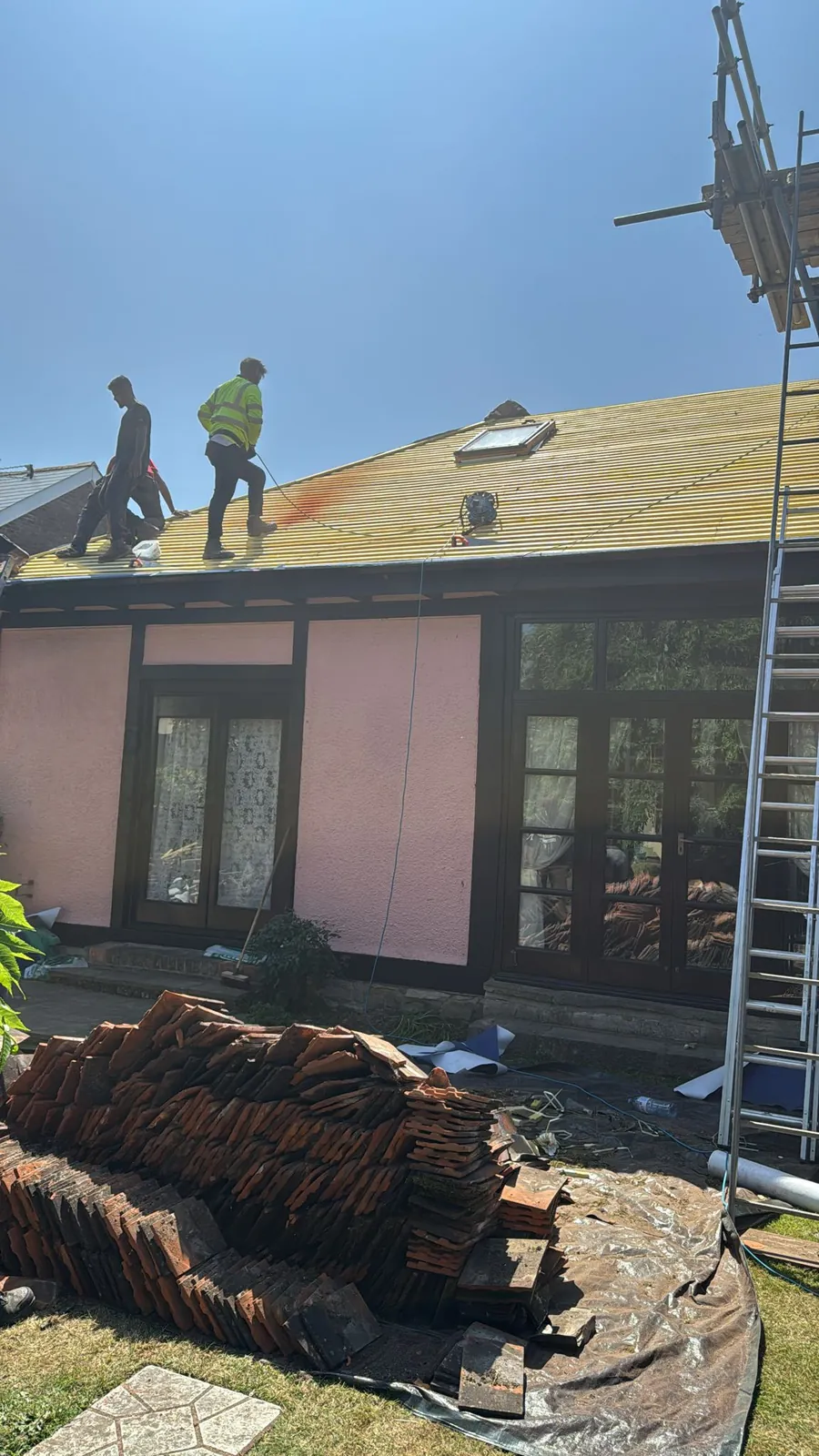 Old tiles stacked as the team strips a bungalow roof