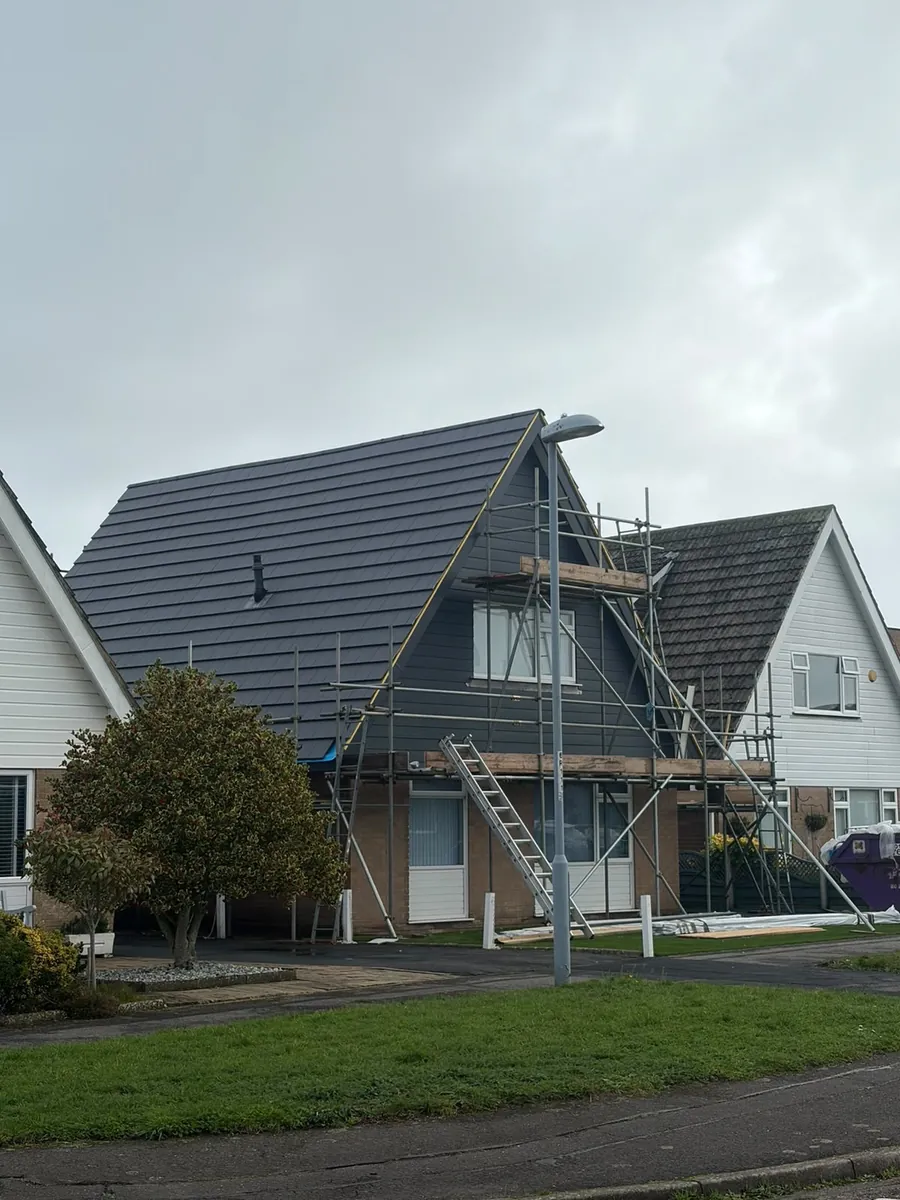 New grey tiled roof on a chalet bungalow under scaffold