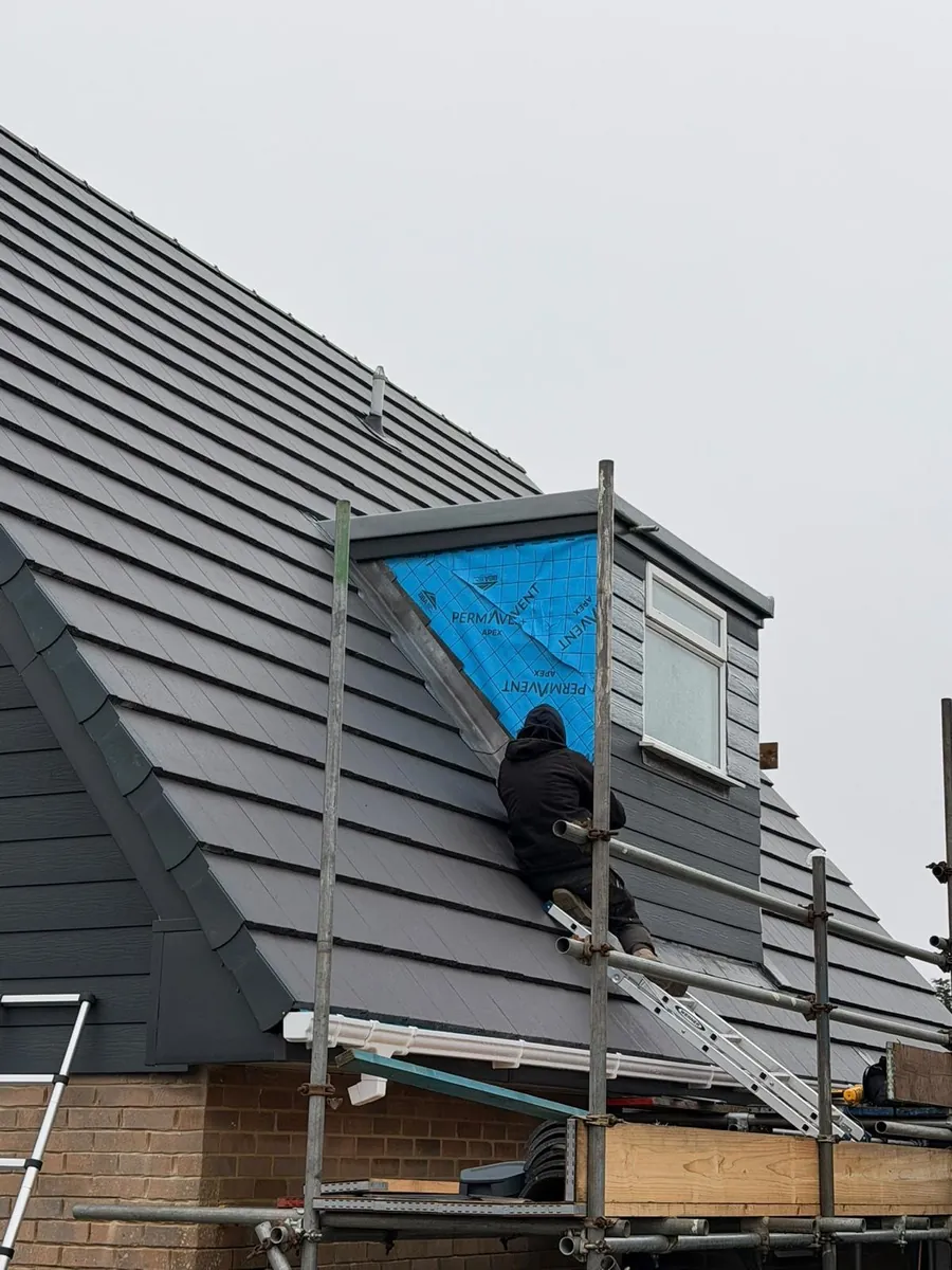 Roofer at a dormer cheek wrapped in membrane