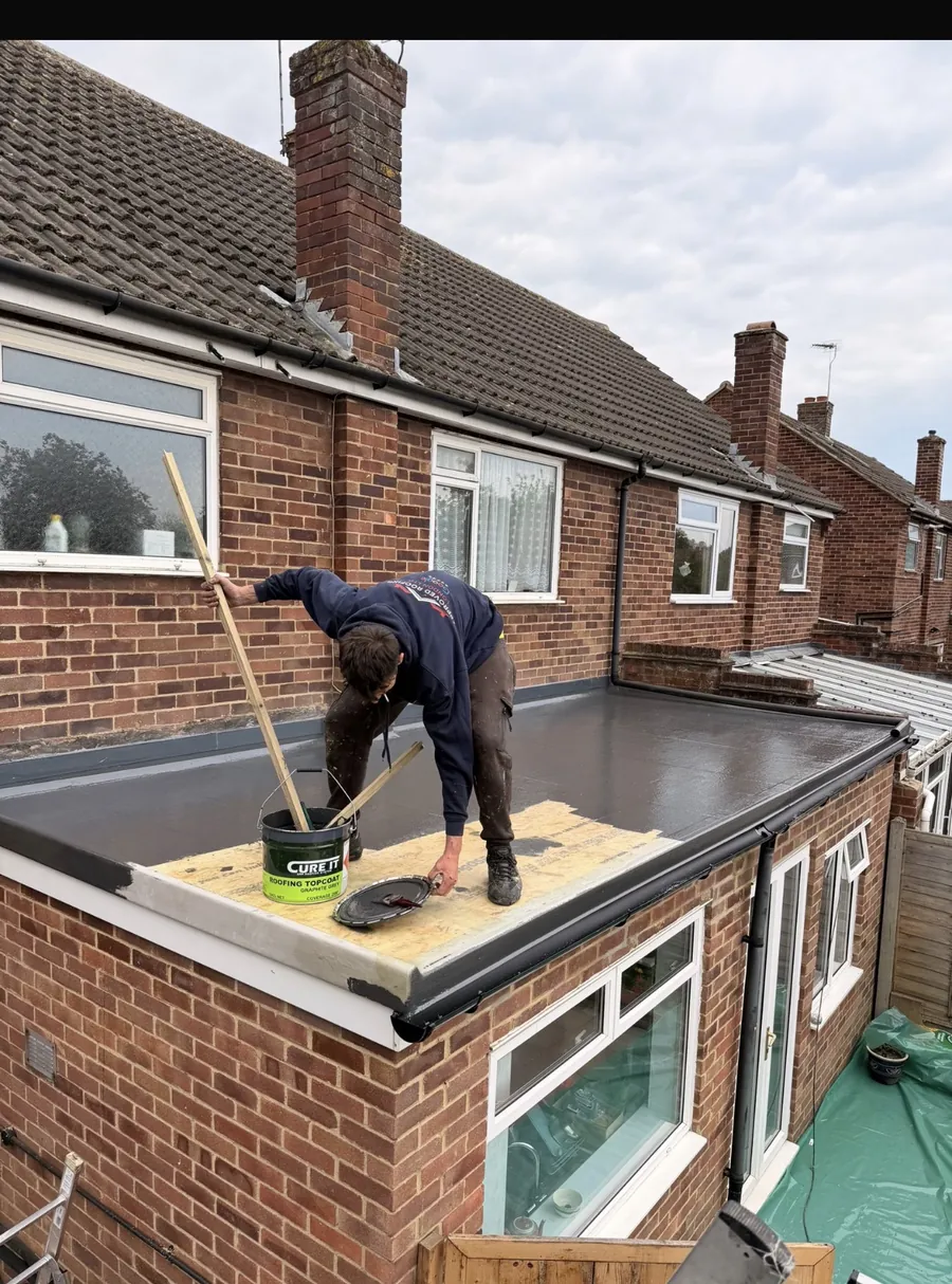 Roofer coating a GRP flat roof on an extension