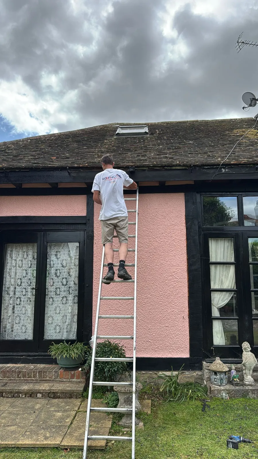 Painting the render on a cottage from a ladder