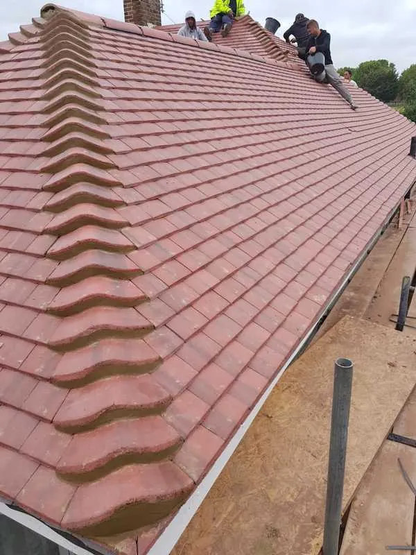 Roofers finishing a plain tile roof
