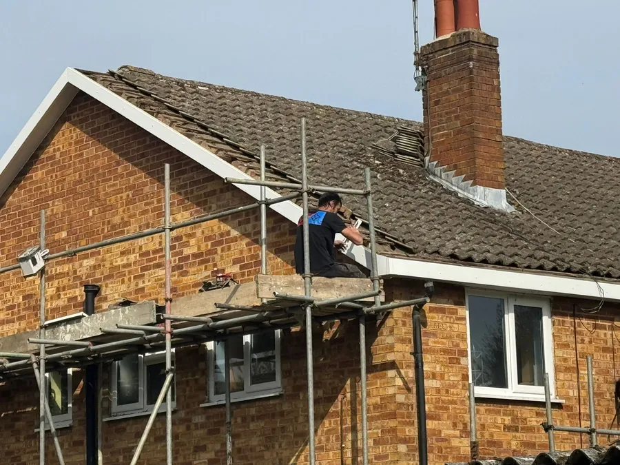 Roofer on the scaffold re-tiling a semi-detached house