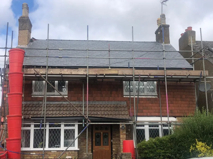 Semi-detached house under scaffold with a rubbish chute