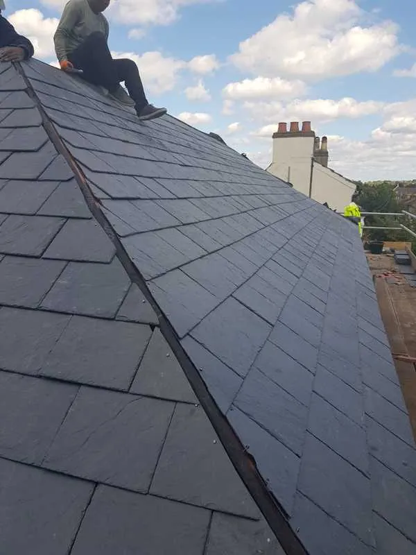 Roofer working along the ridge of a new slate roof