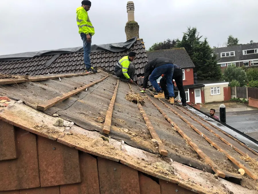 Team in hi-vis stripping old tiles back to the battens